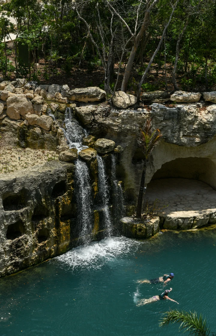 Pessoas nadando nos rios cristalinos com cachoeira do Hotel Xcaret México